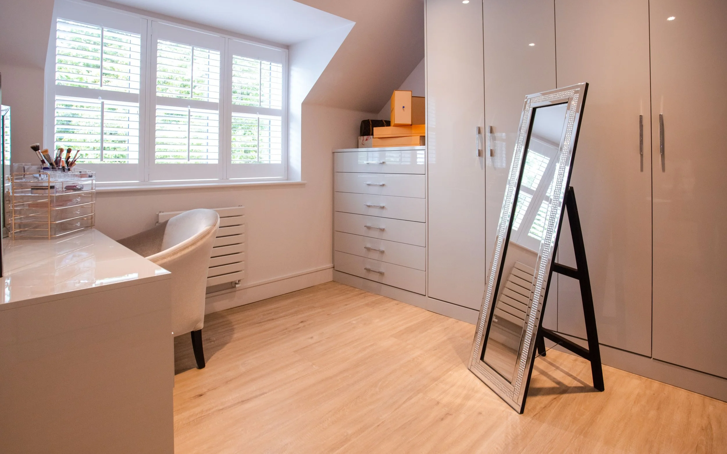 Organised dressing room with fitted wardrobes, drawers and a clear, uncluttered floor.