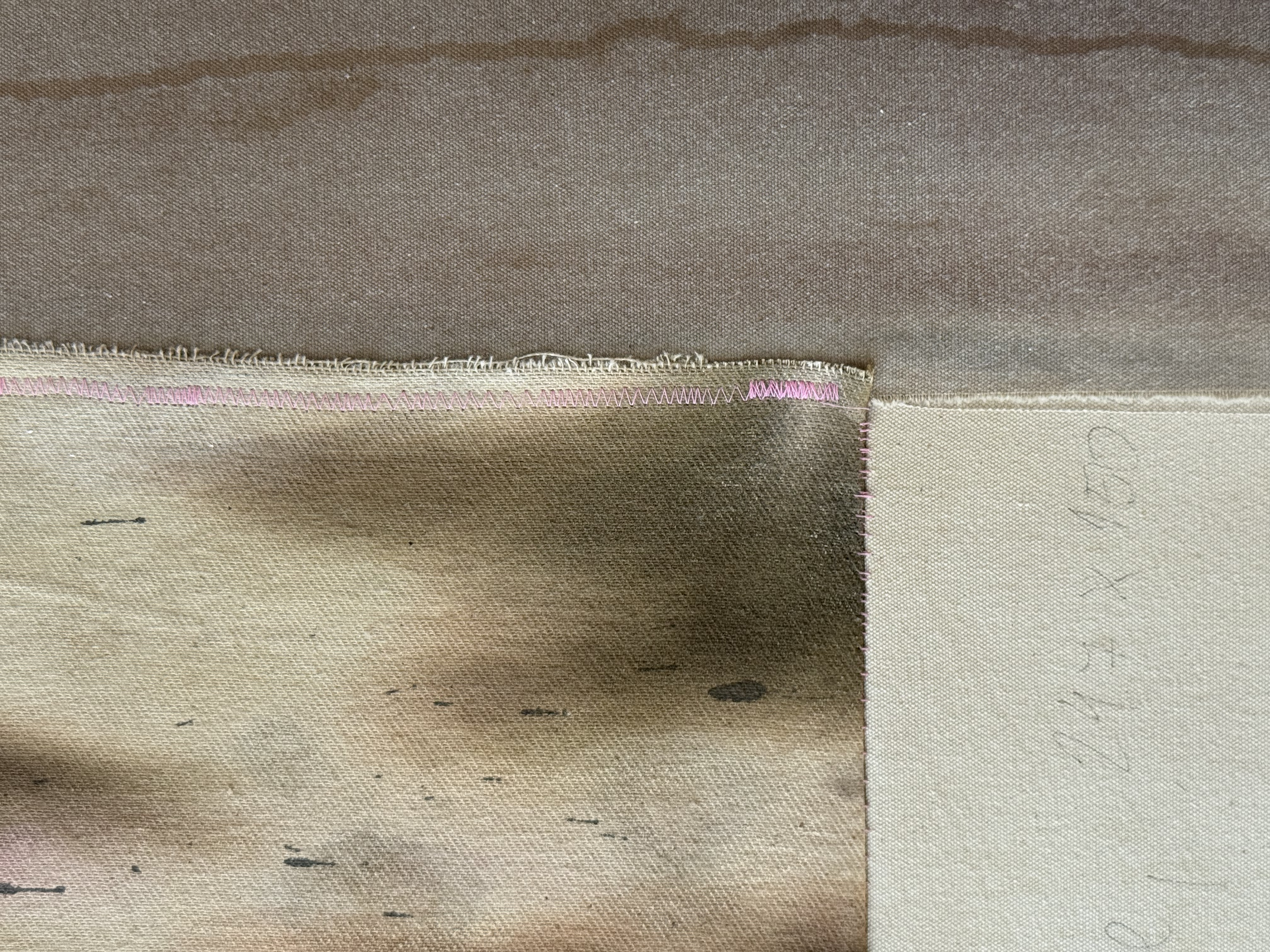 Close-up view of layered fabric pieces sewn together with pink stitches.