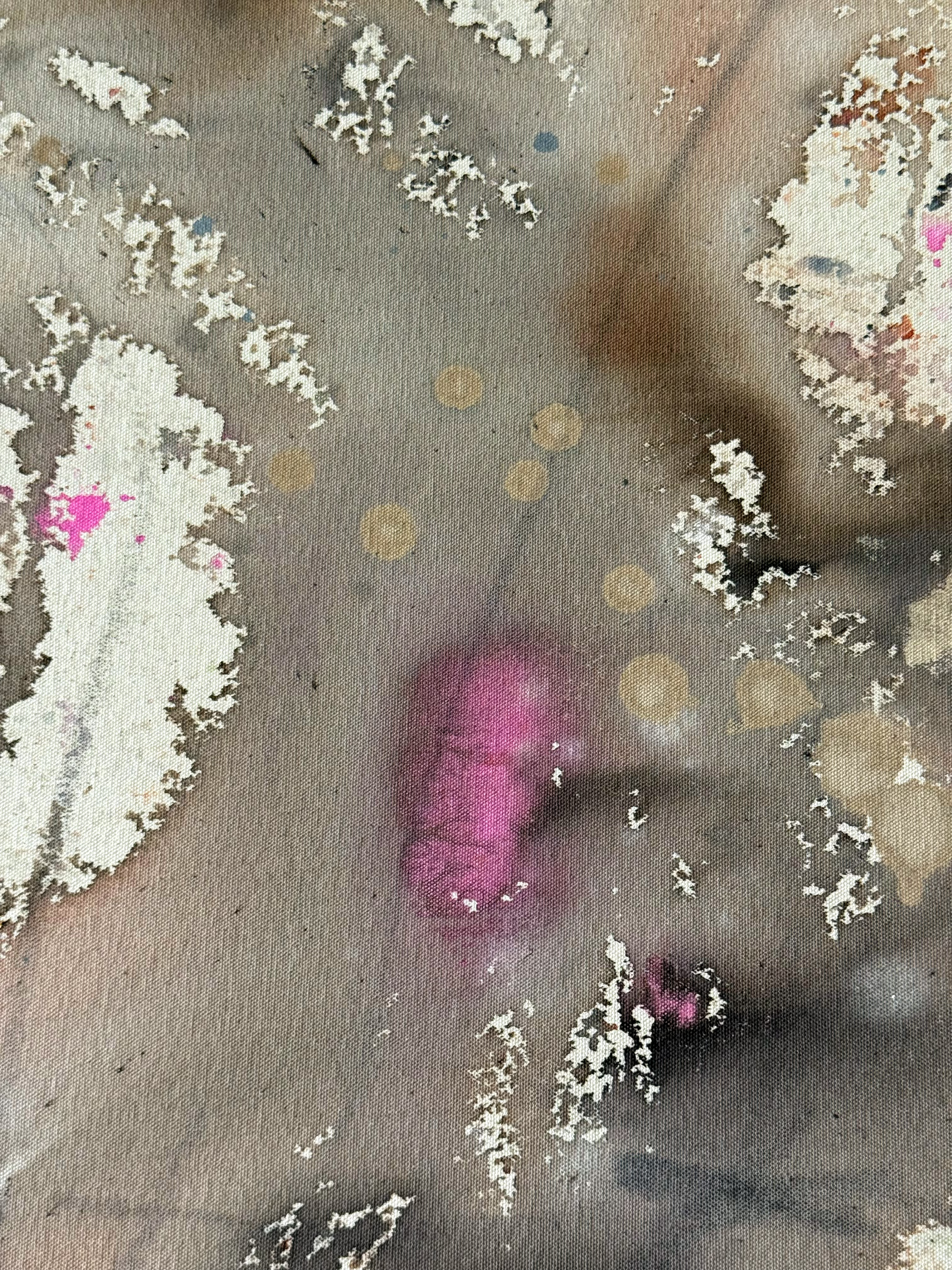 Close-up of a fabric surface with snowflake patterns, a purple streak, and scattered small colorful spots.