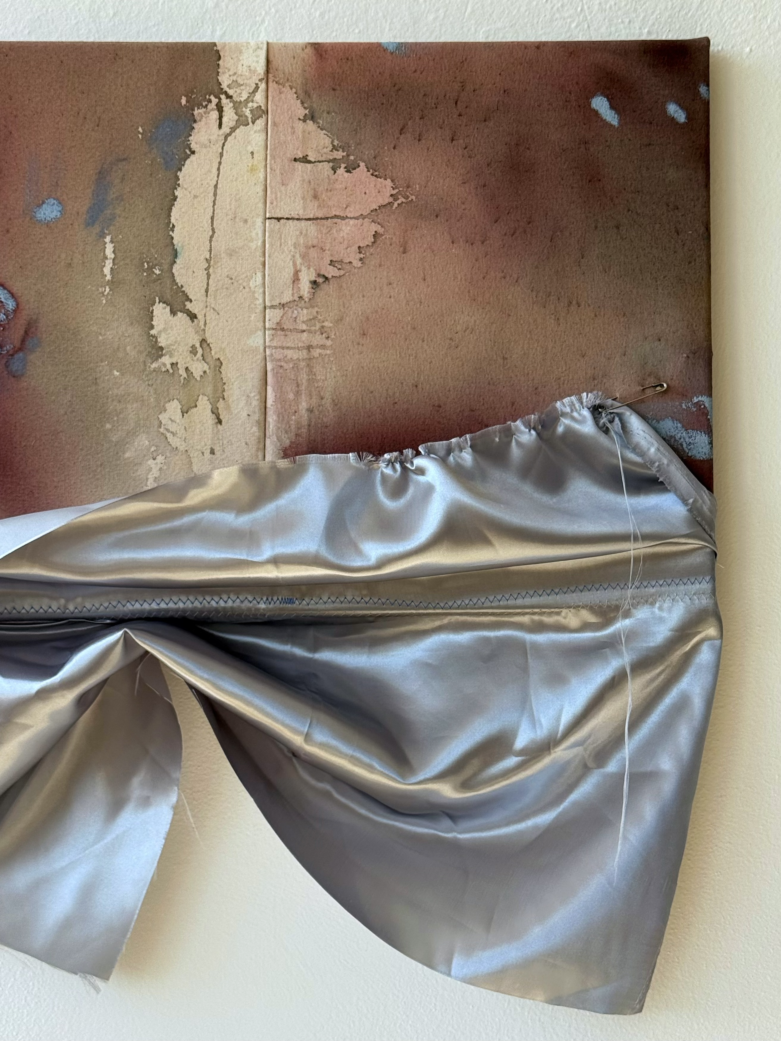A mixed media artwork featuring a watercolor painting of a pink tree with a brown and beige background, with a silver, satin-like fabric draped at the bottom.