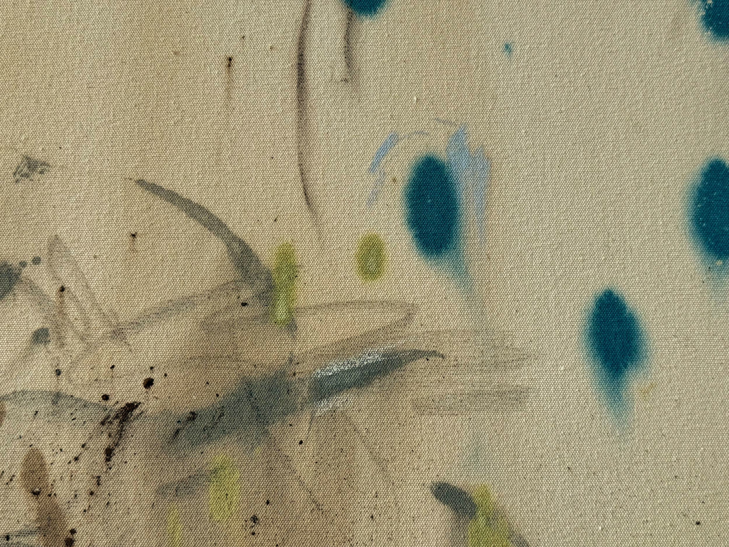 Close-up image of a textured surface with various colors and scattered black specks, resembling fabric or paper with ink or paint spots.