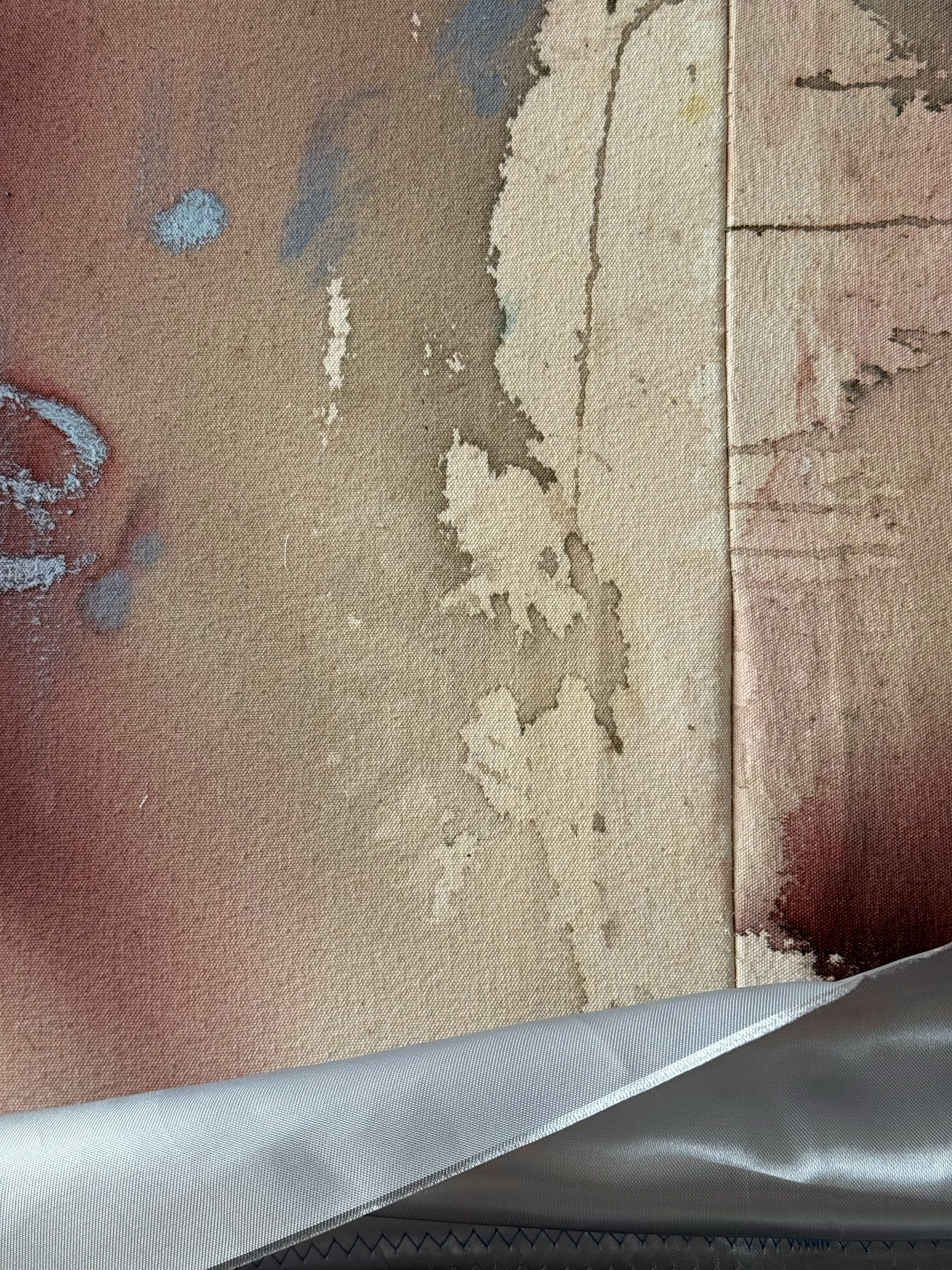 A close-up of a fabric with a peeling, worn, cracked pattern in shades of beige, brown, and gray.