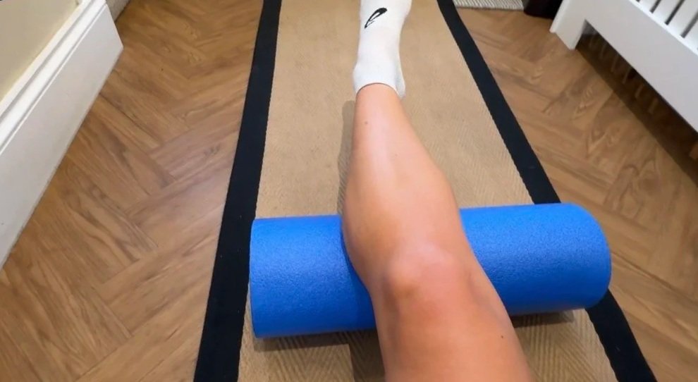 female leg over blue foam roller