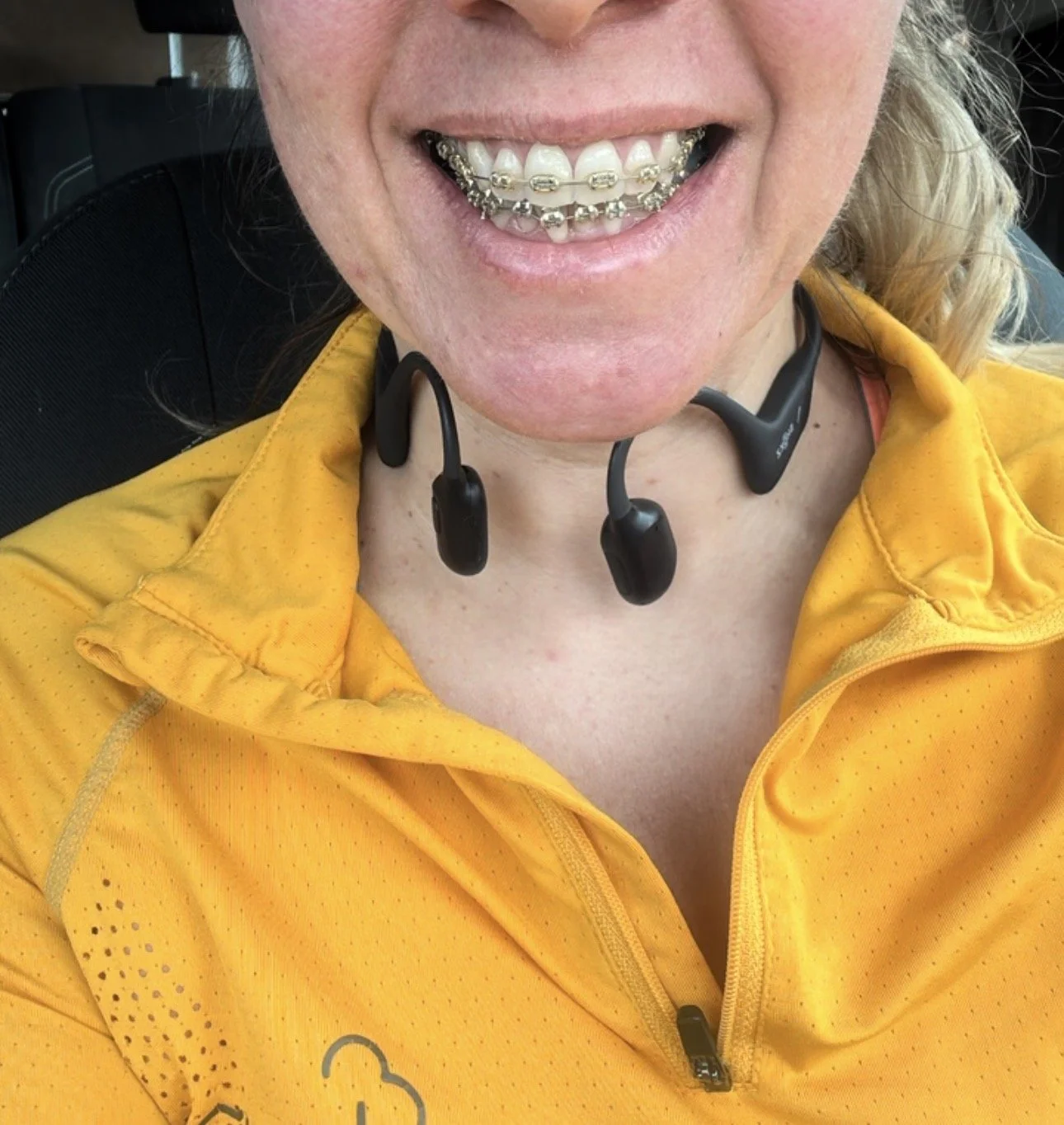 female with headphones around next and wearing orange top