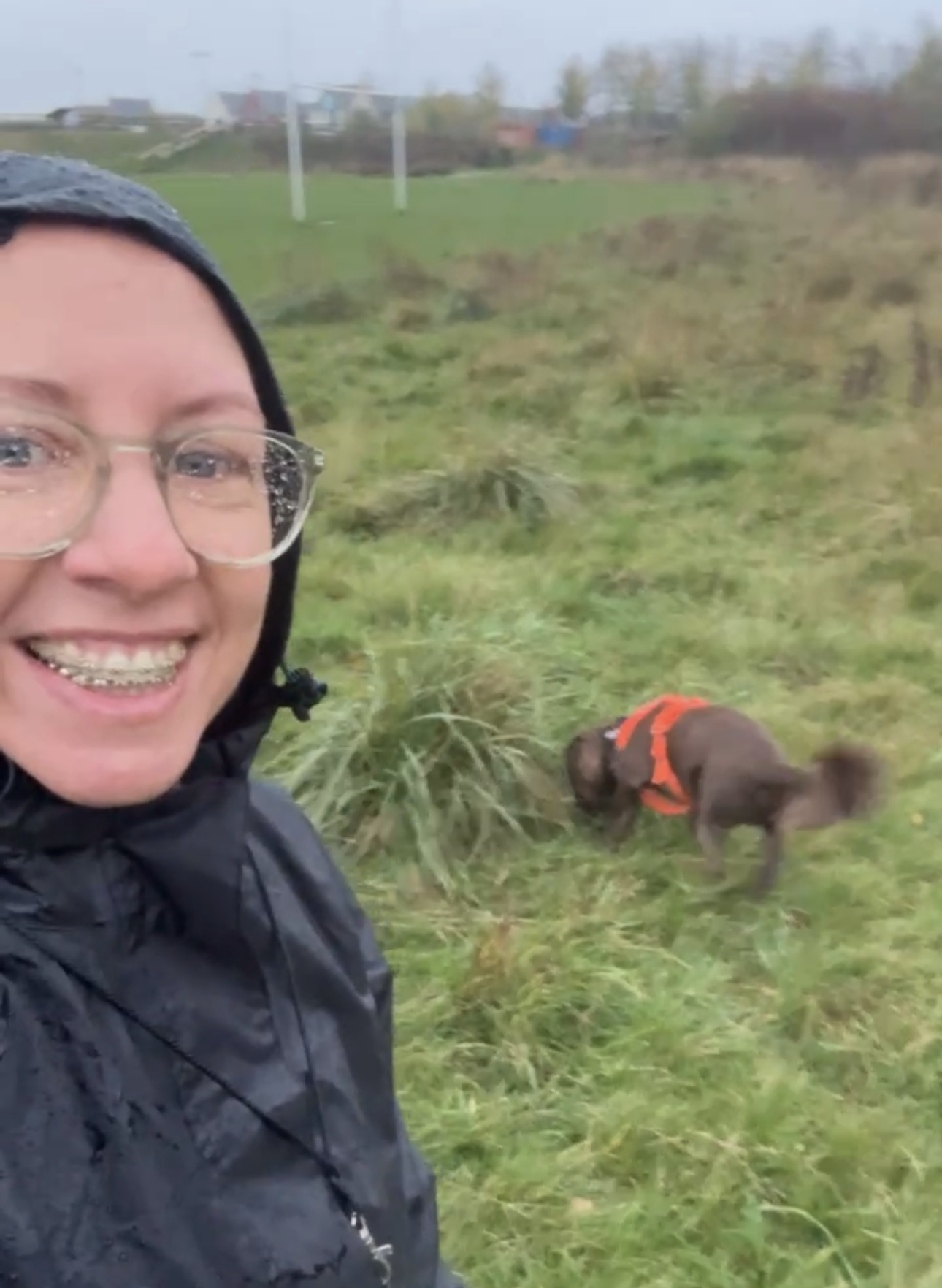 rainy day, on a field of grass, female in black rain coat and cocker spaniel dog