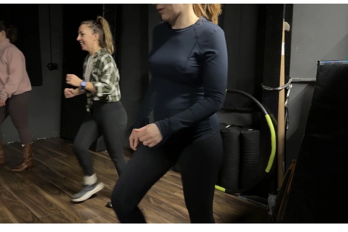 2 women at line dancing class, in motion dancing with smiles on faces