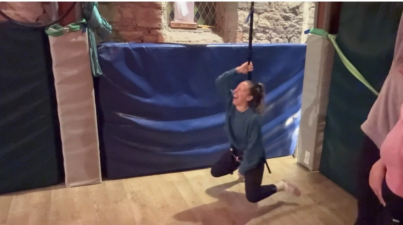 woman in bungee fitness class, laughing and hanging from the ceiling in old church