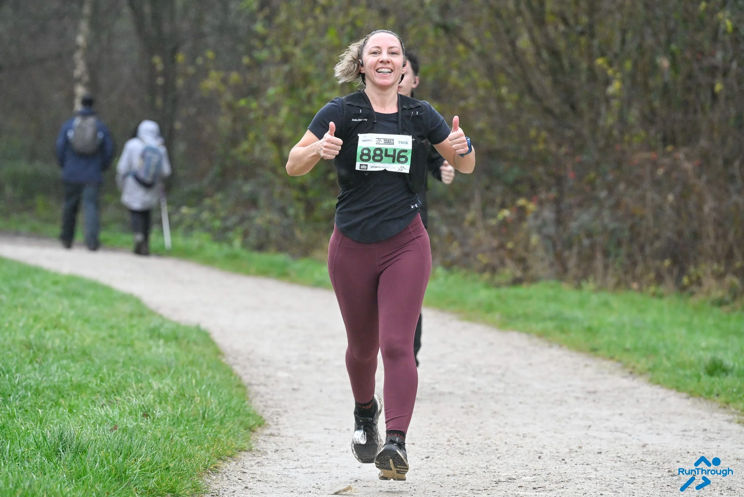 woman running in a race smiling and thumbs up at the camera