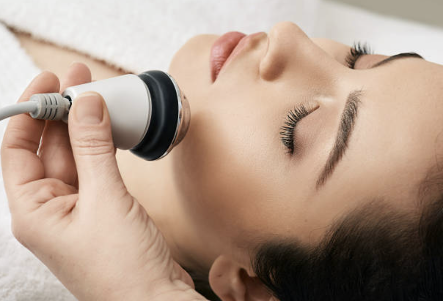 Close-up of a woman receiving a facial treatment with a handheld ultrasonic device on her face.