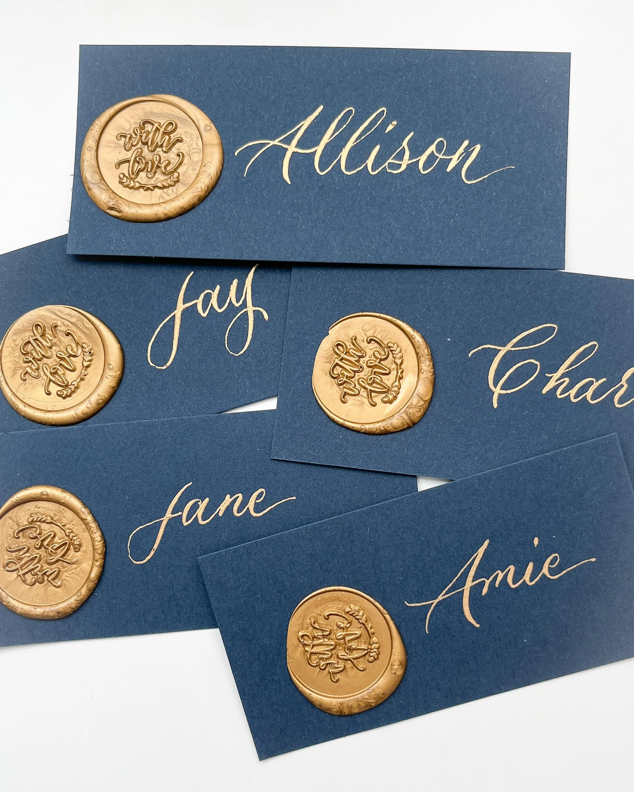 Blue cards with gold wax seals and elegant gold handwritten names.