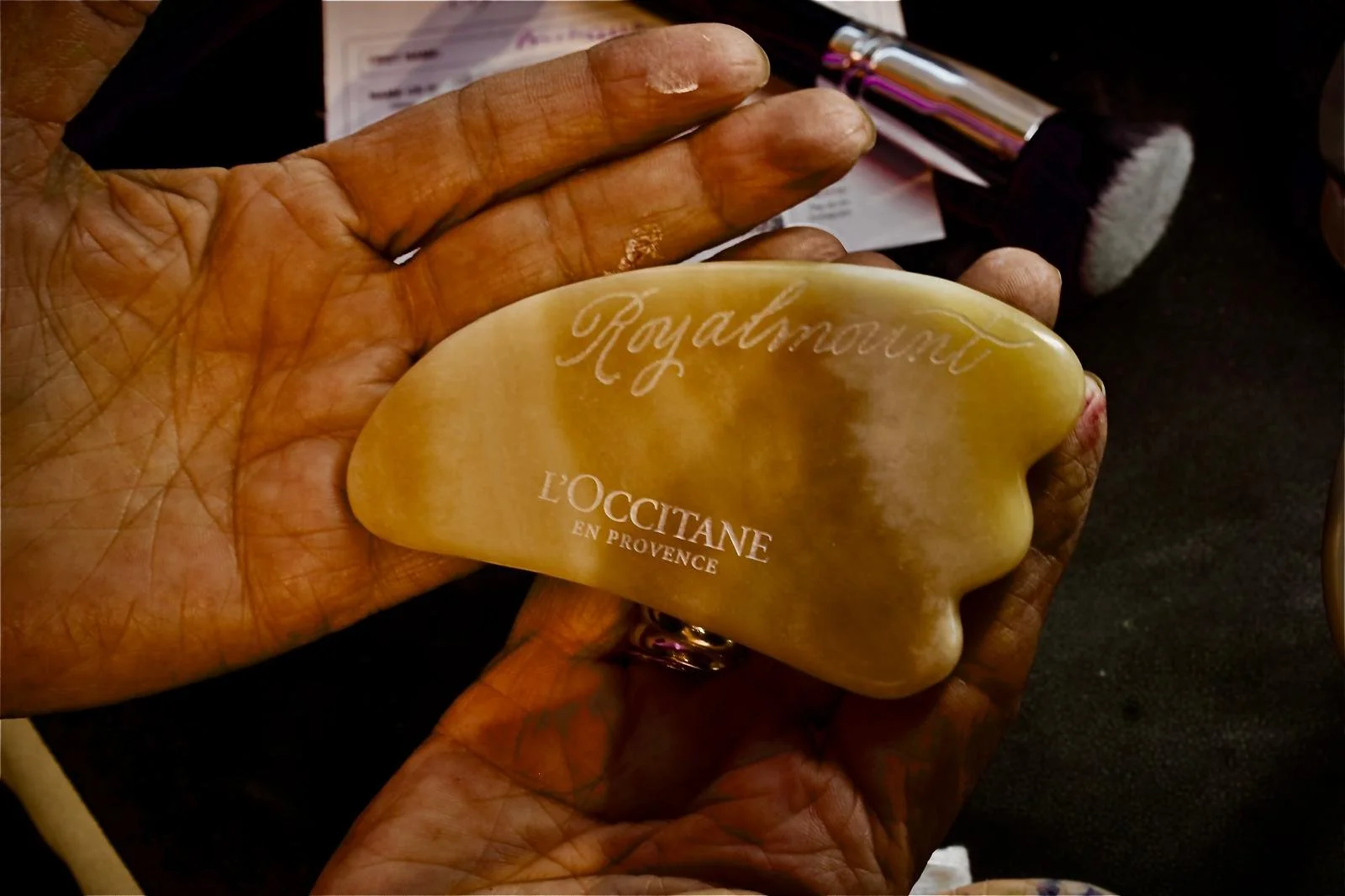 A hand holding a beige soap bar with the words 'Royal moment' and 'L'OCCITANE en Provence' engraved on it.