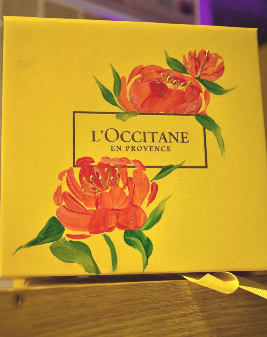 A yellow box with floral illustrations and the text 'L'OCCITANE EN PROVENCE' on it.
