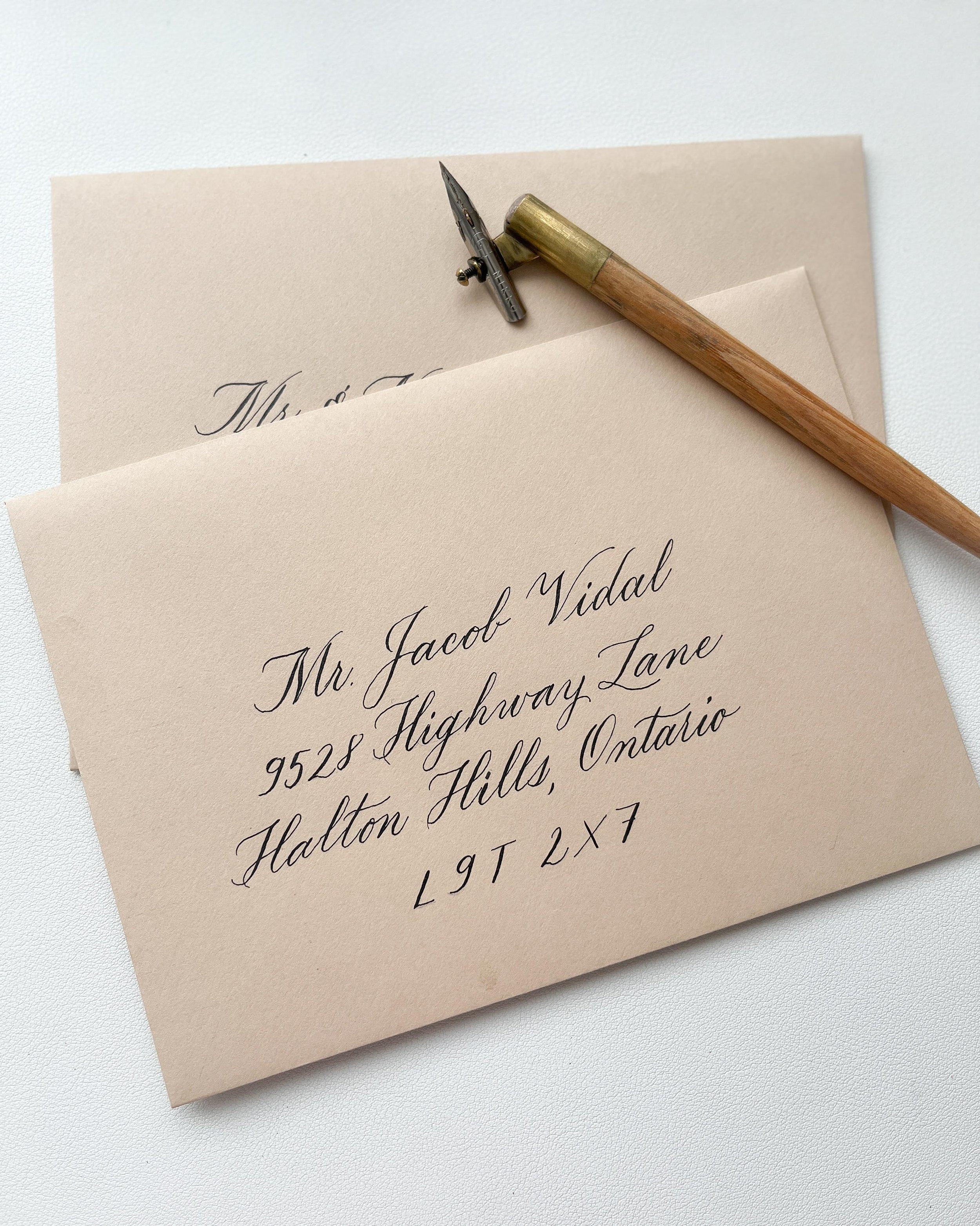 Envelope with calligraphy address and a calligraphy pen on top of it.