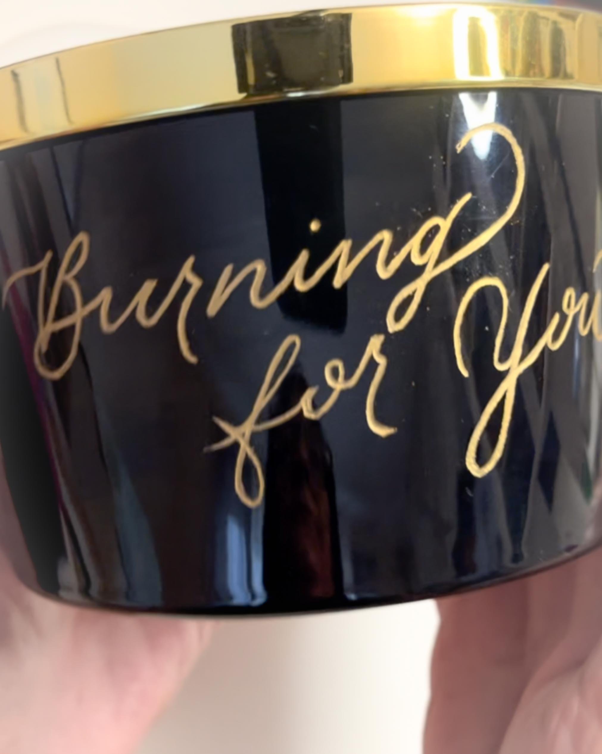 Close-up of a black jar with gold lettering that reads 'Burning for You'.