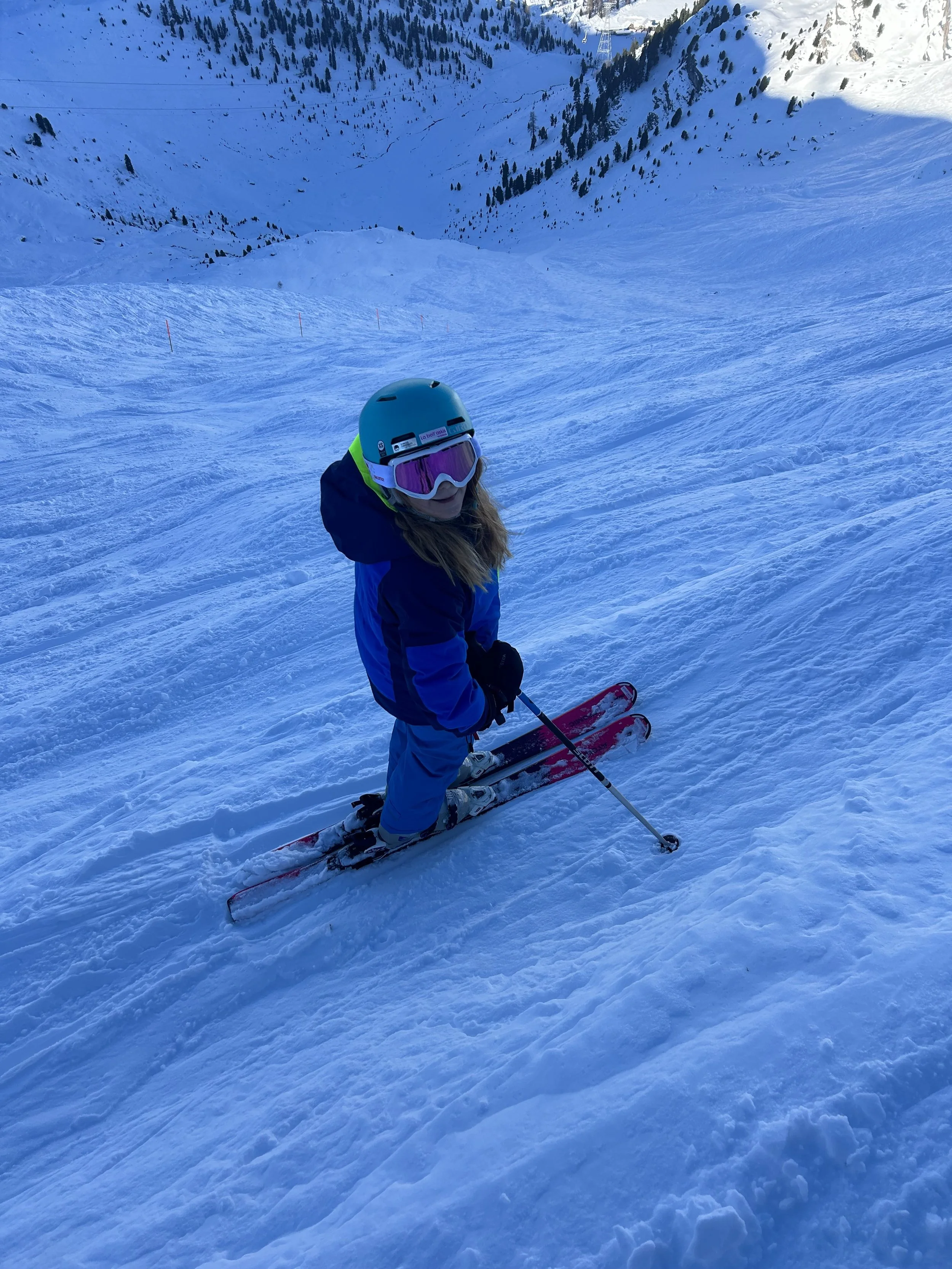 Group of four people dressed in ski gear taking a selfie on a snowy mountain with ski lifts and equipment in the background.