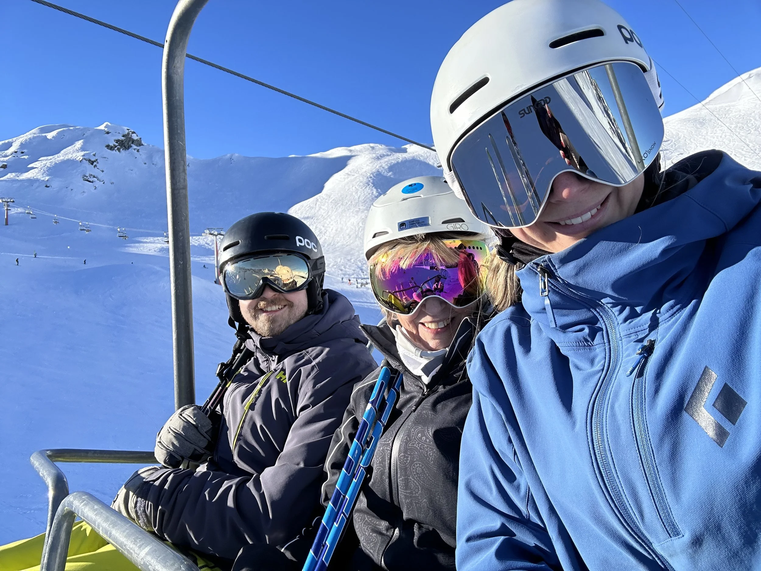 A young girl in ski gear, including a helmet, goggles, and a jacket, standing on skis in the snow on a mountain slope during daytime.