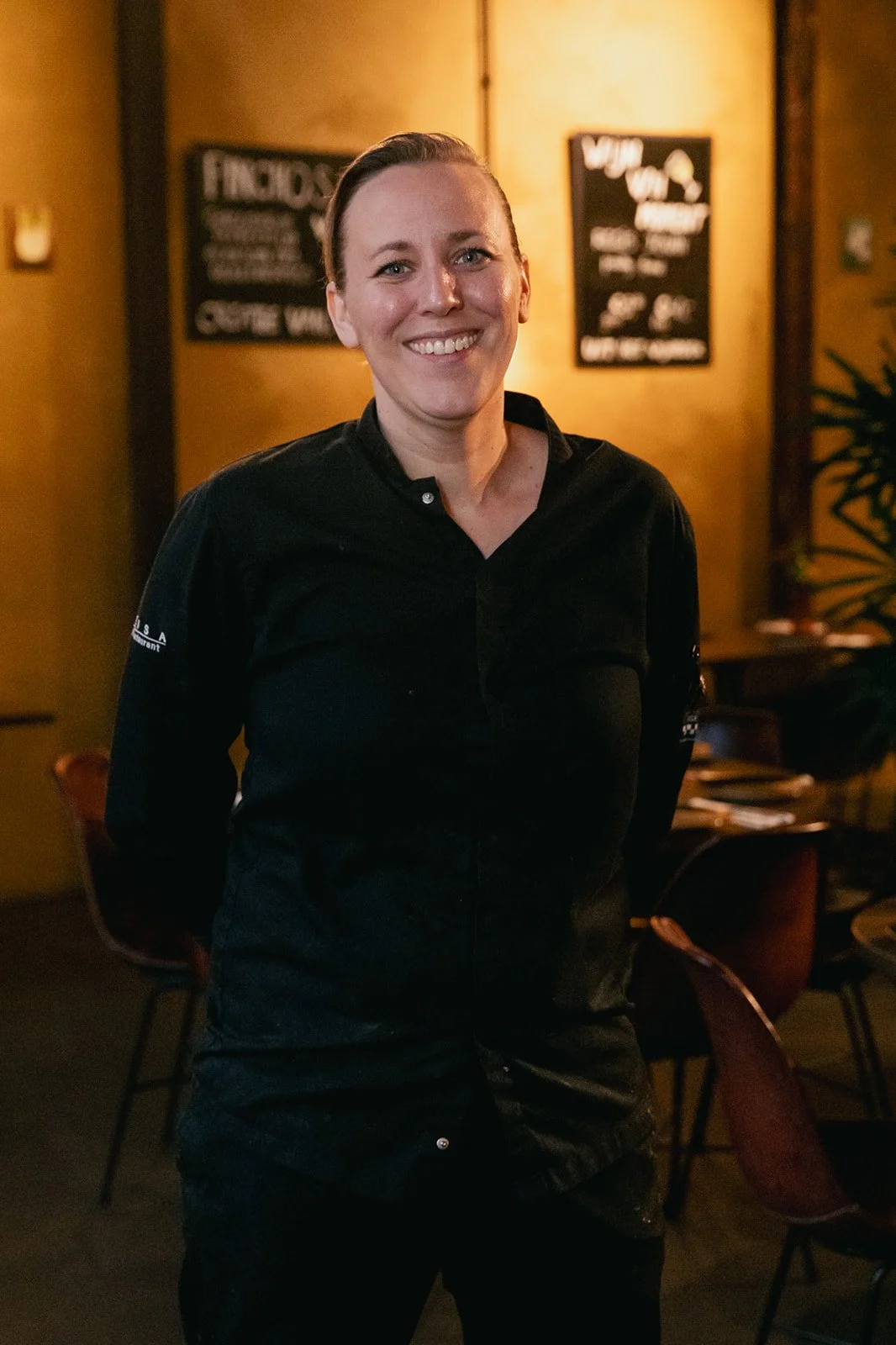De chef van Heisa lacht naar de camera in een zwart koksoutfit.