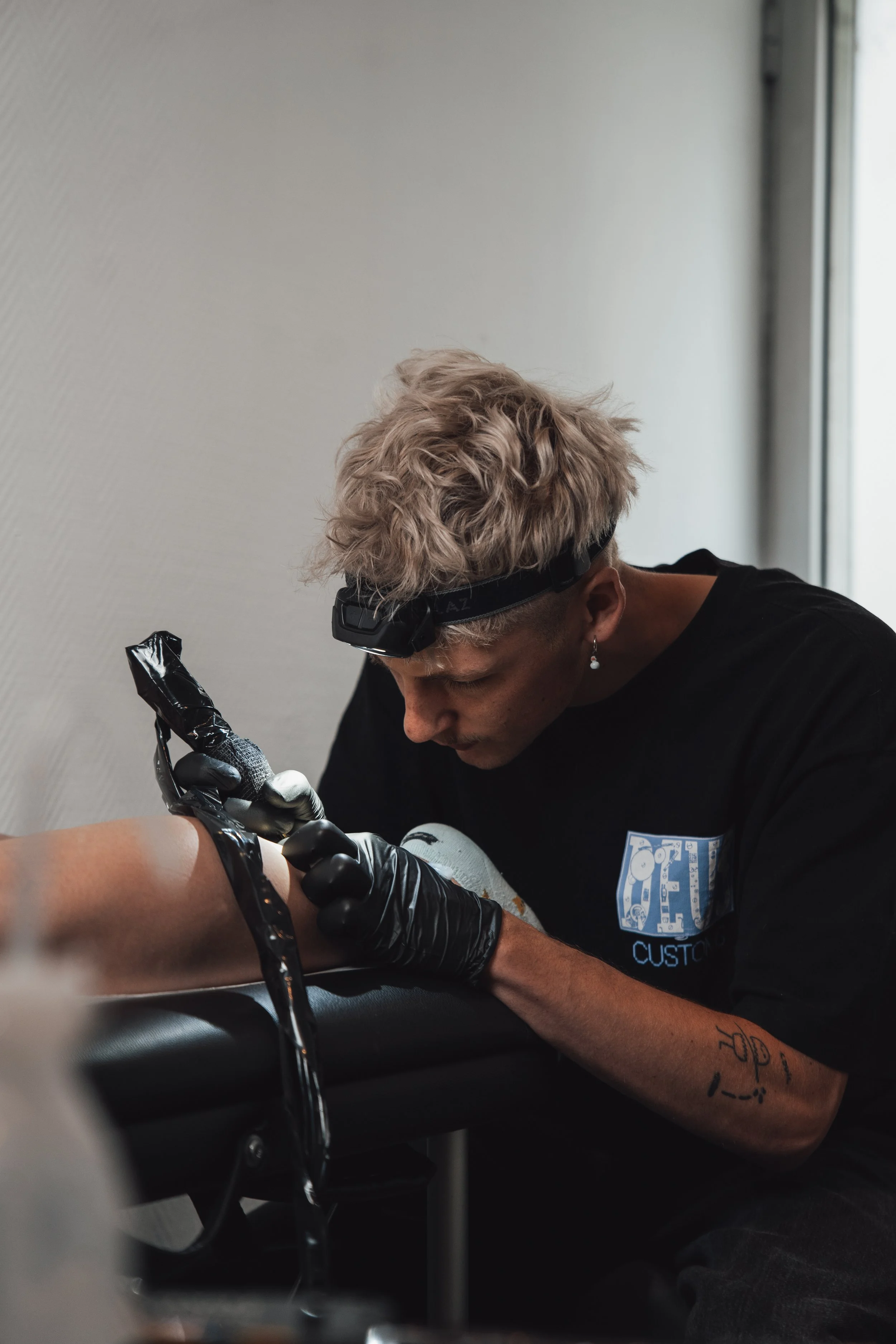 Tatoueur en train de tatouer un bras.