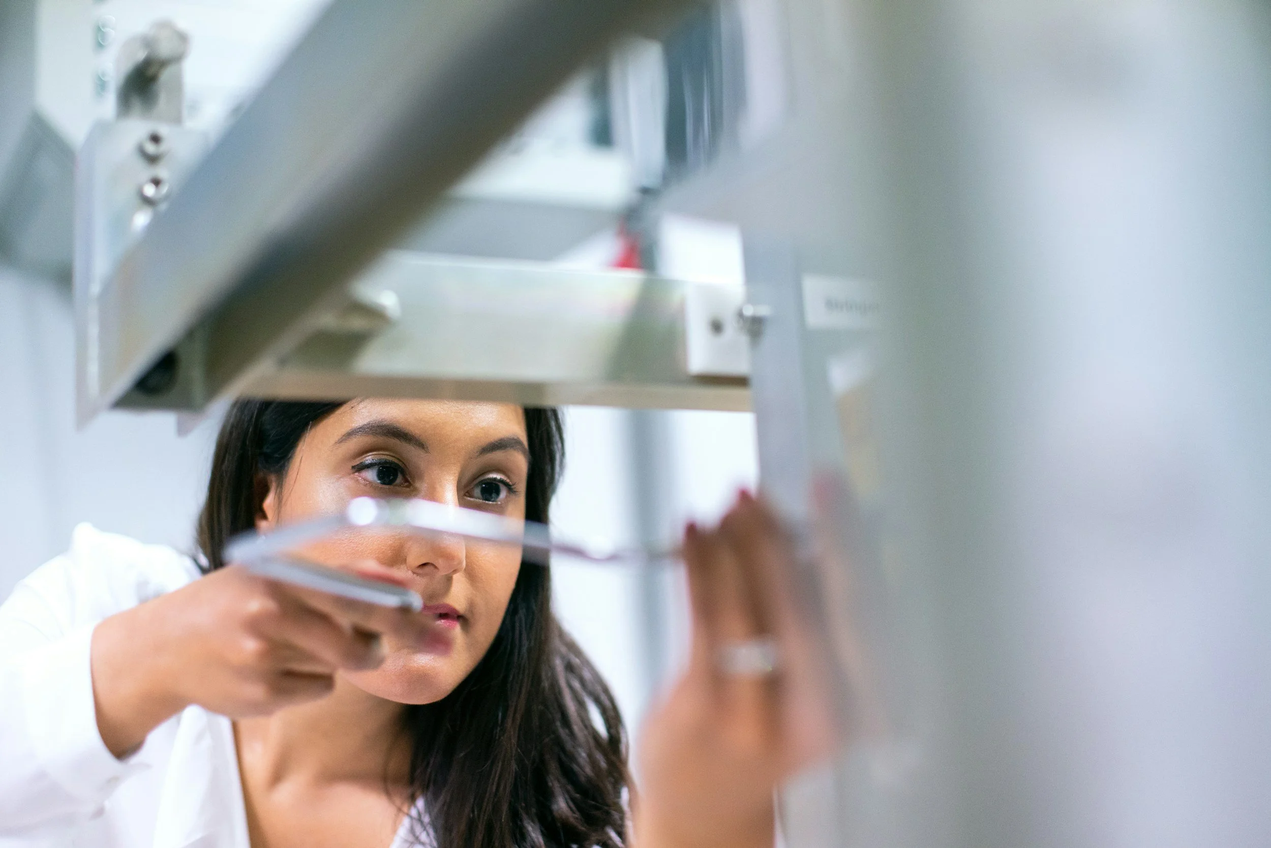 A woman scientists in a laboratory placing a test tube into a metal rack.