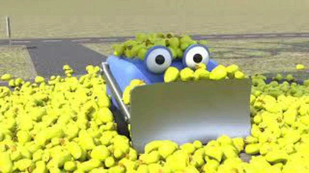 A cartoonish machine with googly eyes and a blue body, surrounded by numerous yellow tennis balls on the ground.