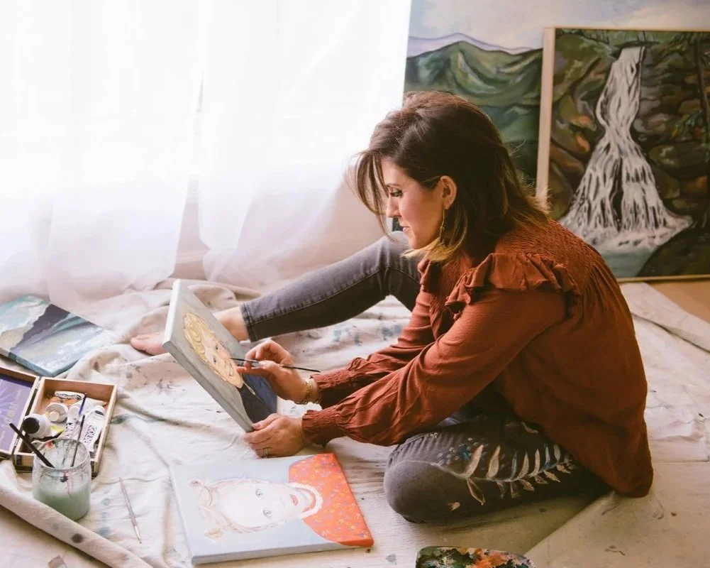 Woman painting on canvas in her art studio with paintings and art supplies around