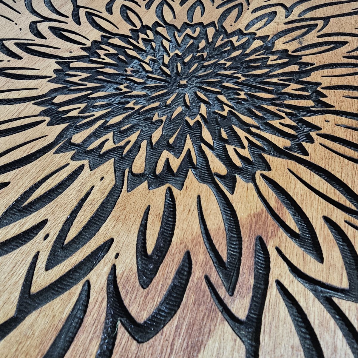 Close-up of laser-engraved floral pattern on round wooden lazy Susan, showing deep black engraving and wood grain.
