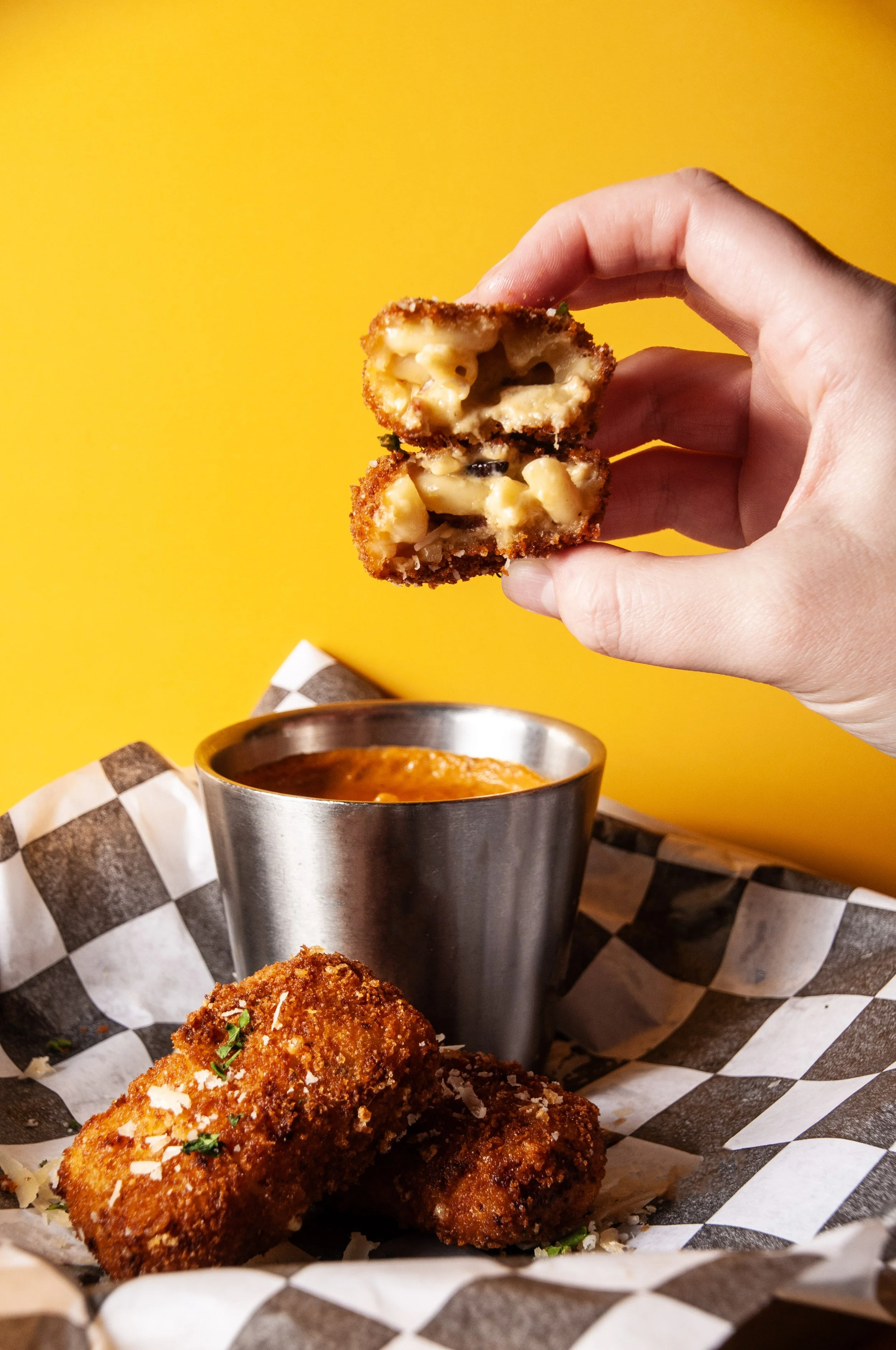 Hand holding a piece of fried bacon mac & cheese bites