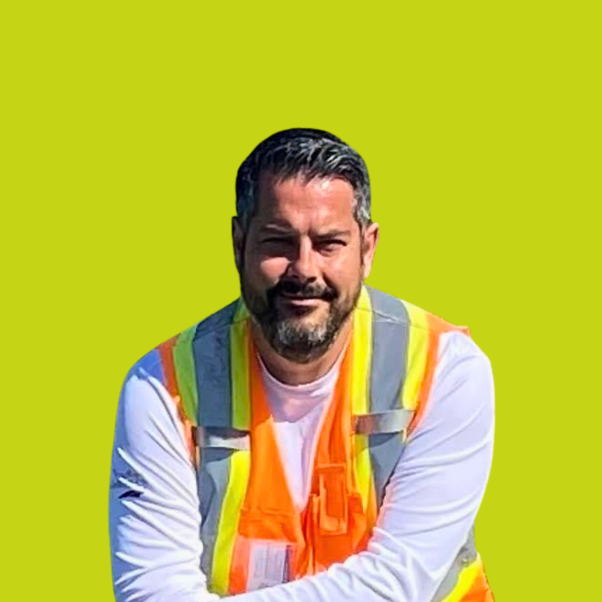 Man with dark hair and beard wearing a white long-sleeve shirt and a high-visibility safety vest against a lime green background.
