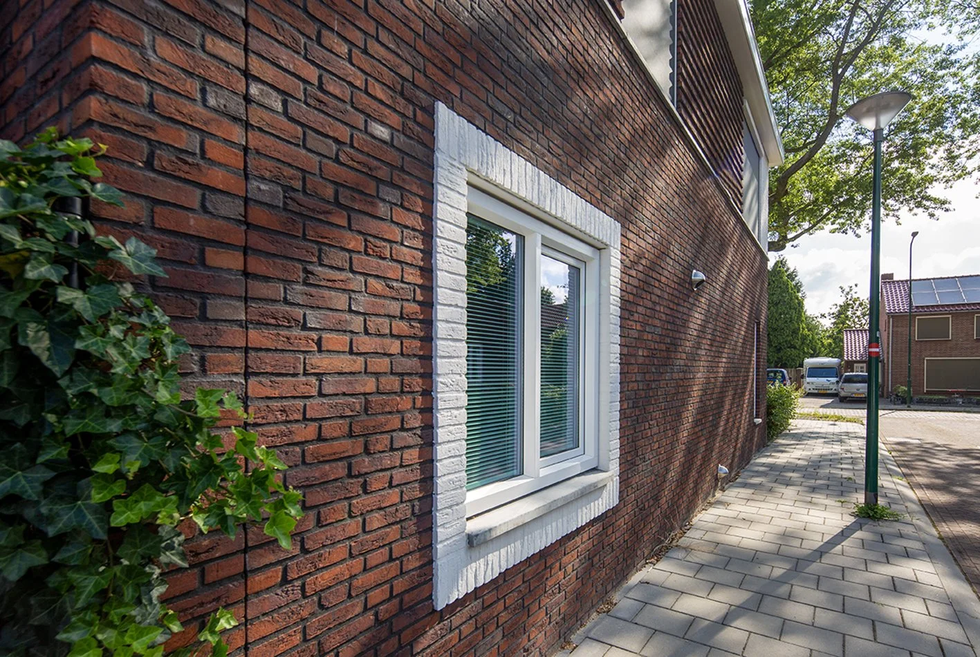 Een rode bakstenen muur met een witte-framed raam gefotografeerd door architectuurfotograaf John van Groenedaal.