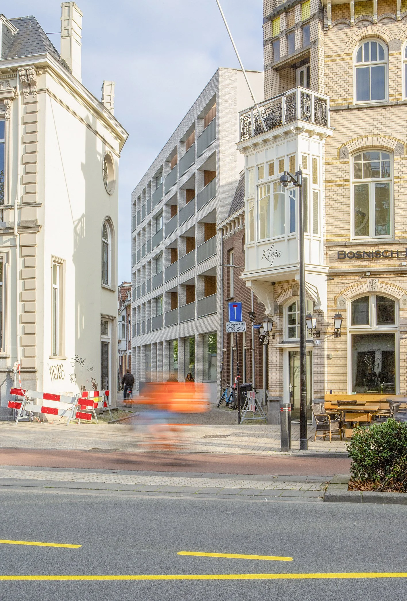 Straatbeeld met een oude en een moderne gebouw, een blauwe fiets, straatverlichting, en een langs de weg geparkeerde fiets.