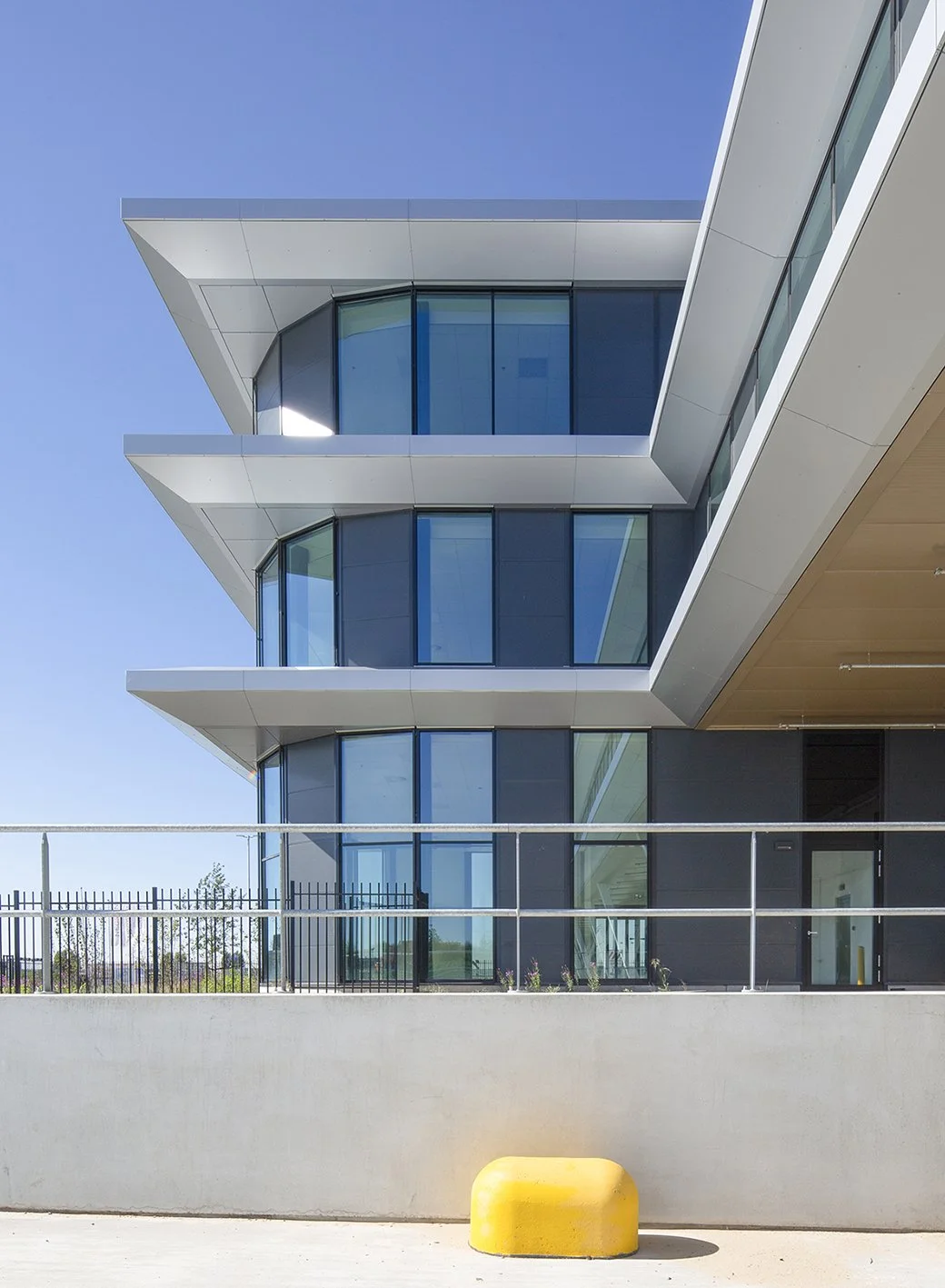 Een modern gebouw met grote ramen en witte afwerkingen, onder een heldere blauwe hemel.