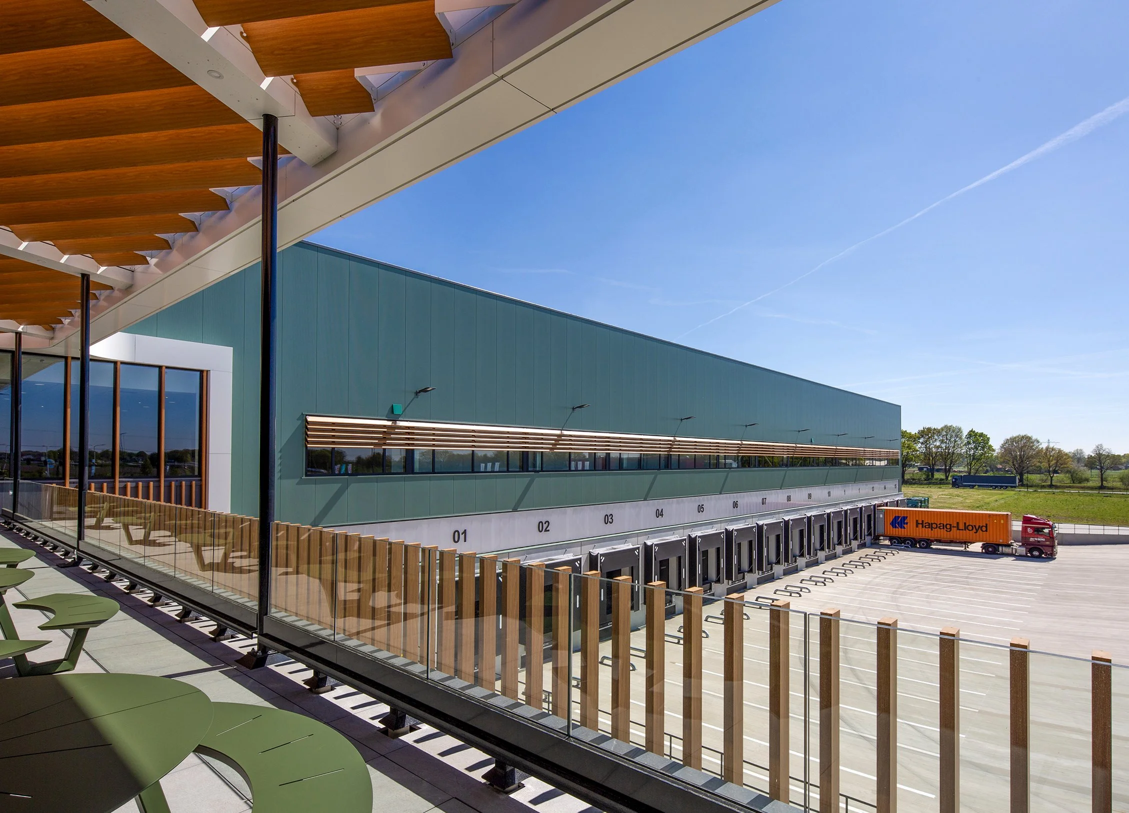 Moderne gebouw met blauwe gevel, houten overkapping gefotografeerd door architectuurfotograaf John van Groenedaal.