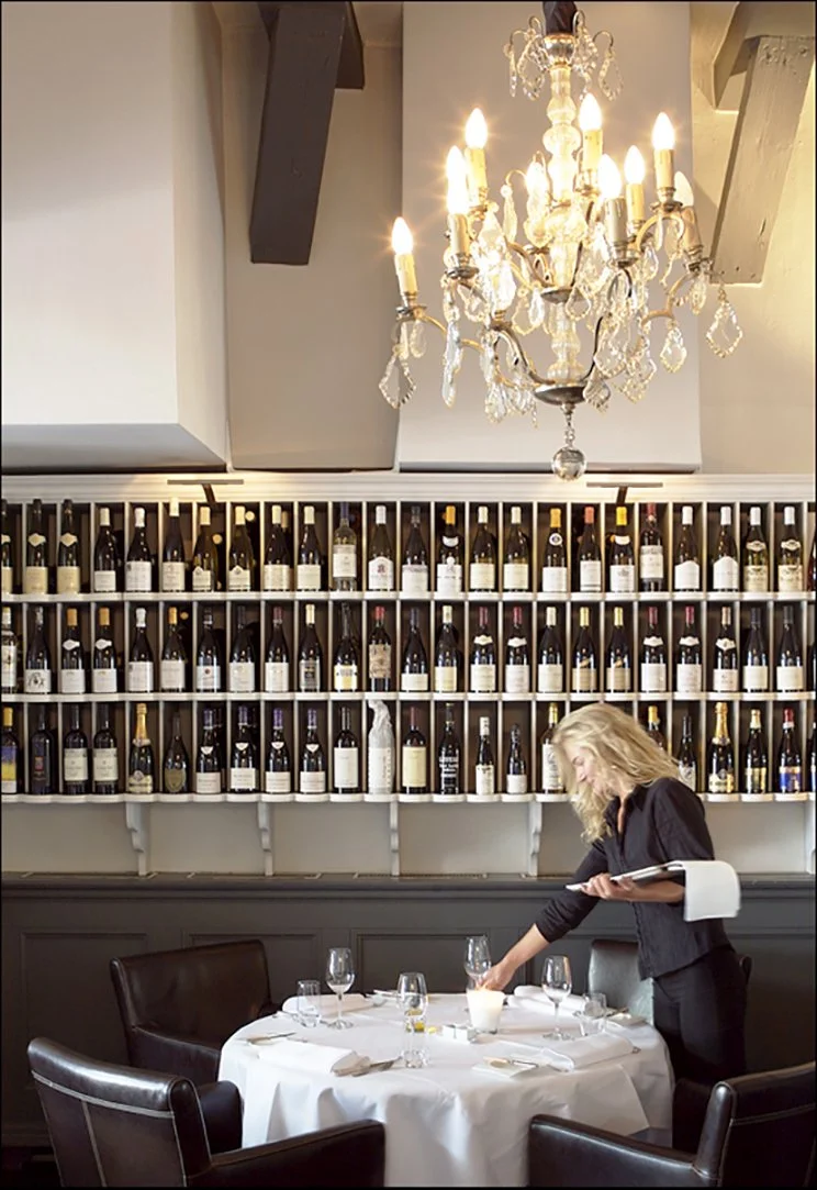 interieurfoto van restaurantmedewerker voor wand met wijn