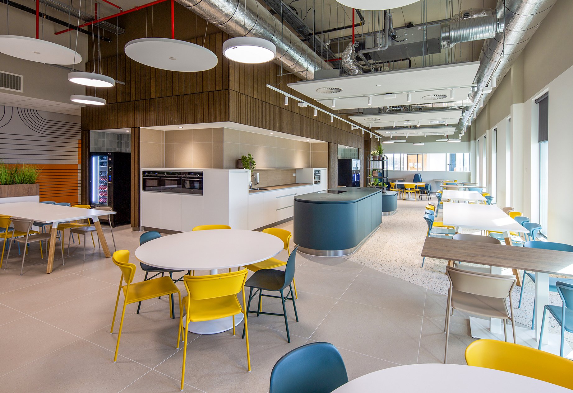 Modern restaurant in Amsterdam gefotografeerd door interieurfotograaf John van Groenedaal met een open keuken met wit en blauw, plafond met decoratieve verlichting en zichtbare technische installaties, grote ramen voor natuurlijk daglicht.