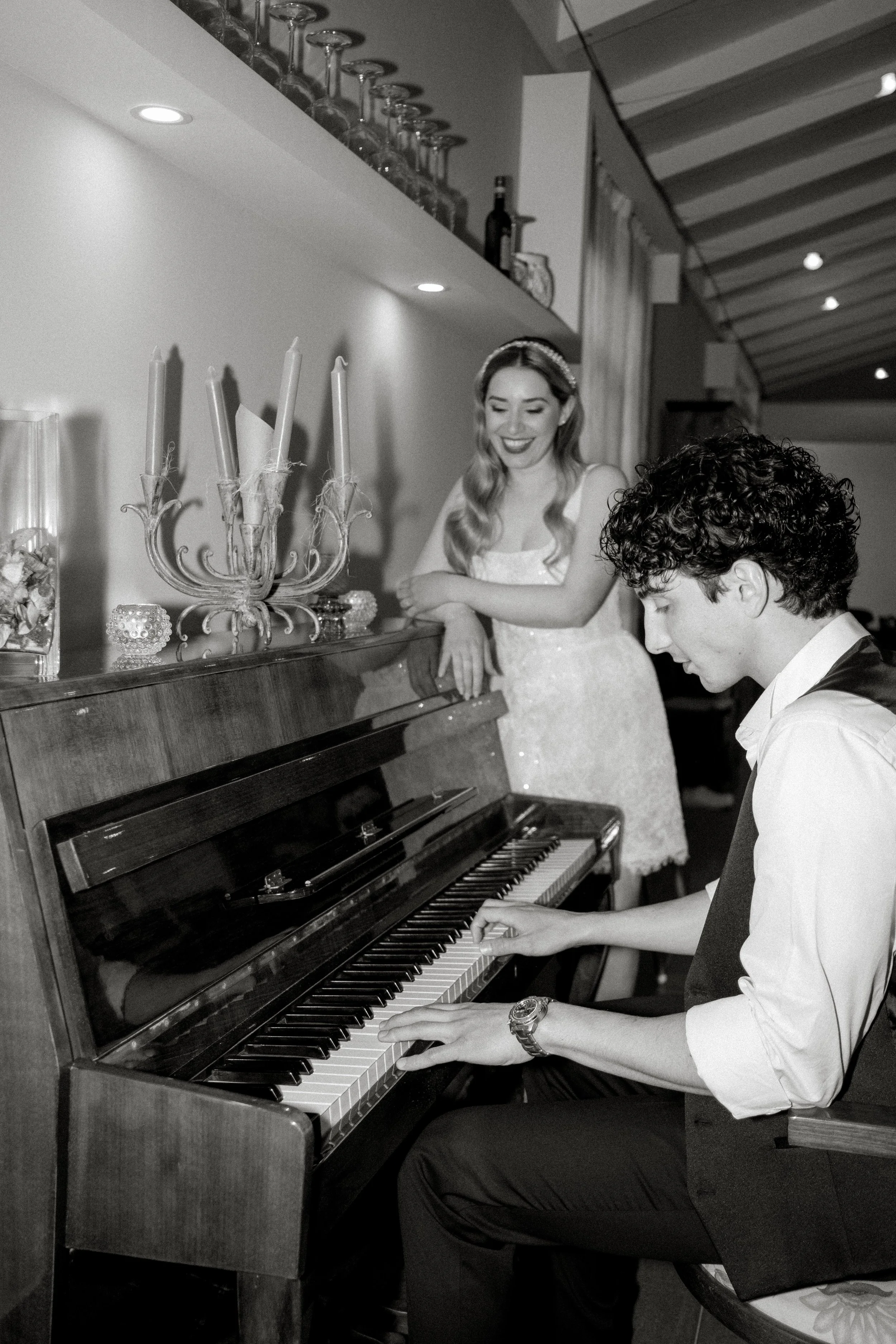 Bride smiling as groom plays the piano during a wedding celebration in Sicily