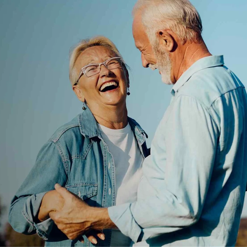 older-couple-smiling-laughing-holding-hands.png