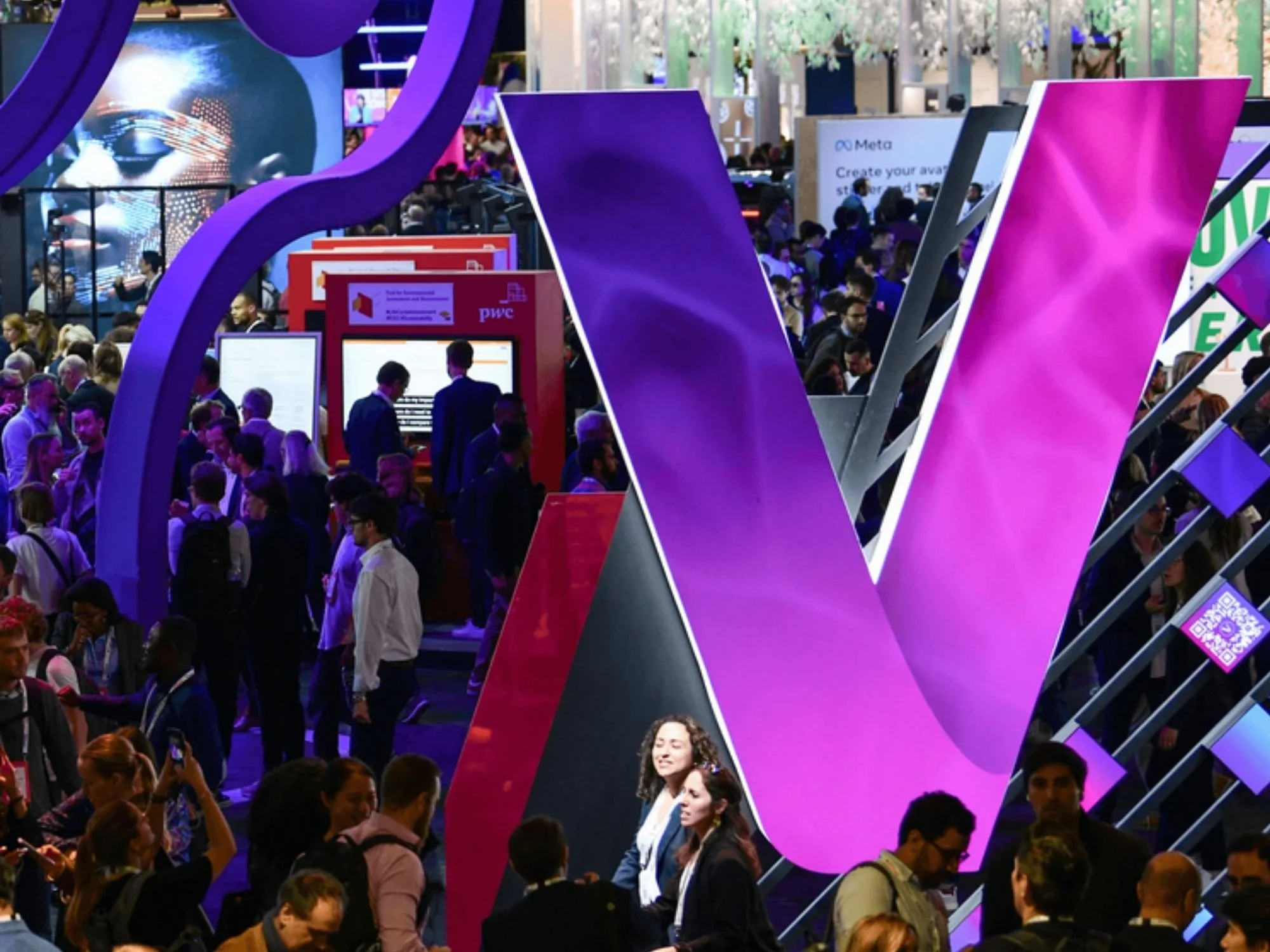 Grand panneau violet et rose VICTIG lors d'une conférence technologique ou d'un salon professionnel très fréquenté.