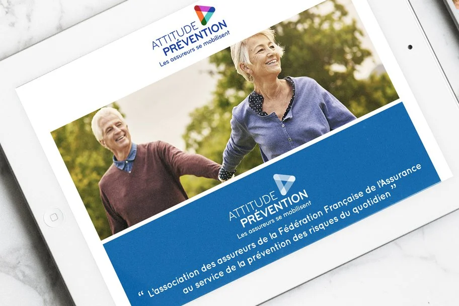 Tablette affichant une brochure pour Attitude Prévention, une compagnie d'assurance, avec une photo de deux femmes âgées souriantes se tenant la main en plein air.