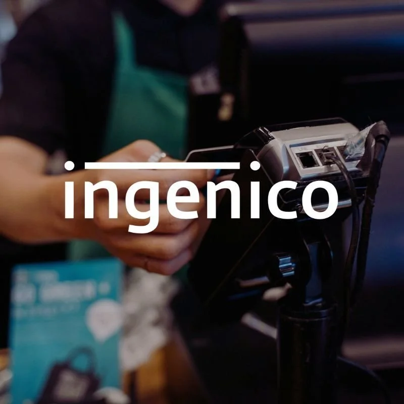 Personne tenant un lecteur de carte avec des fils, effectuant probablement une transaction, avec le mot « ingenico » superposé à l'image.
