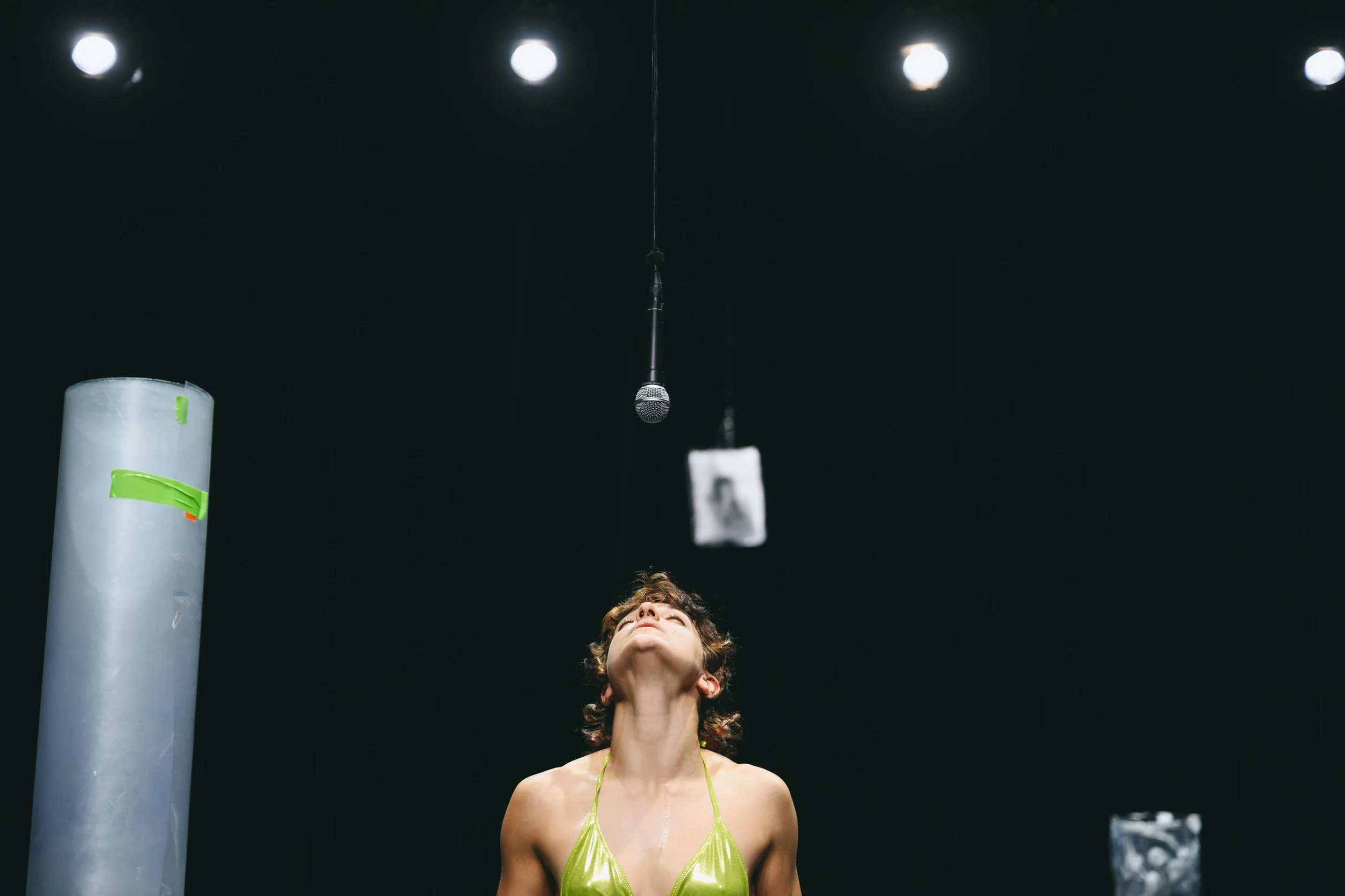A man in a black t-shirt standing against a wall with blue and red lighting.