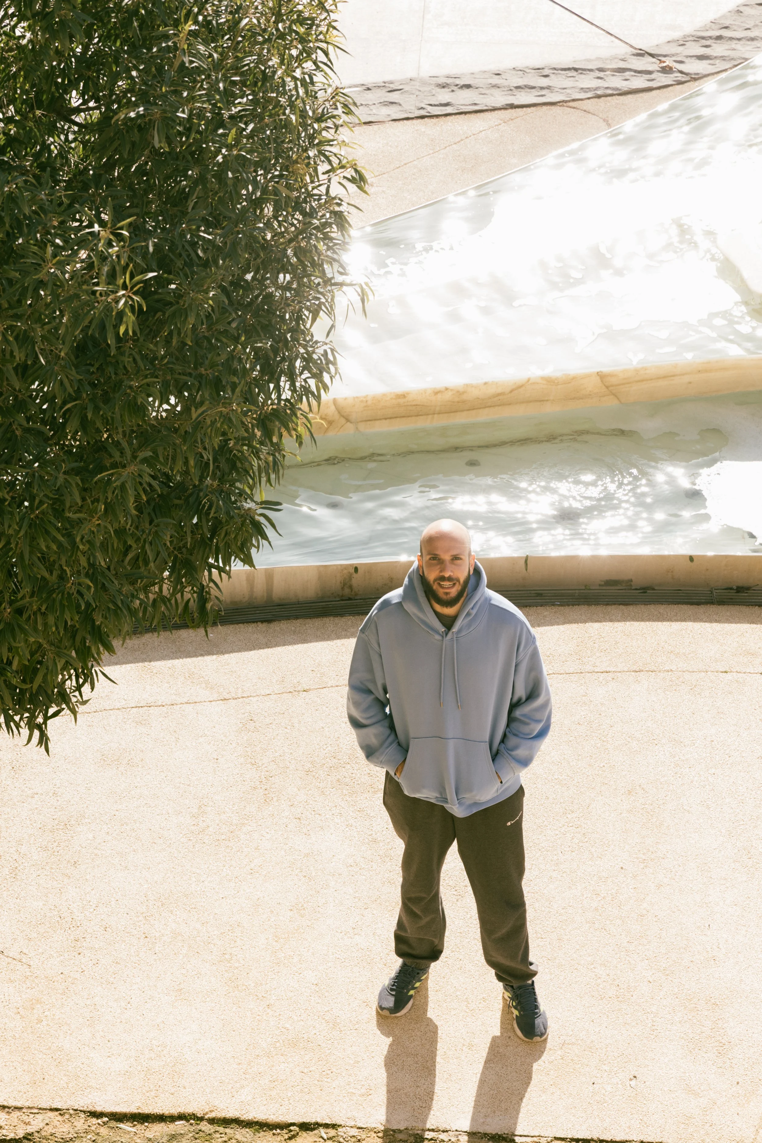 A man in a black t-shirt standing against a wall with blue and red lighting.
