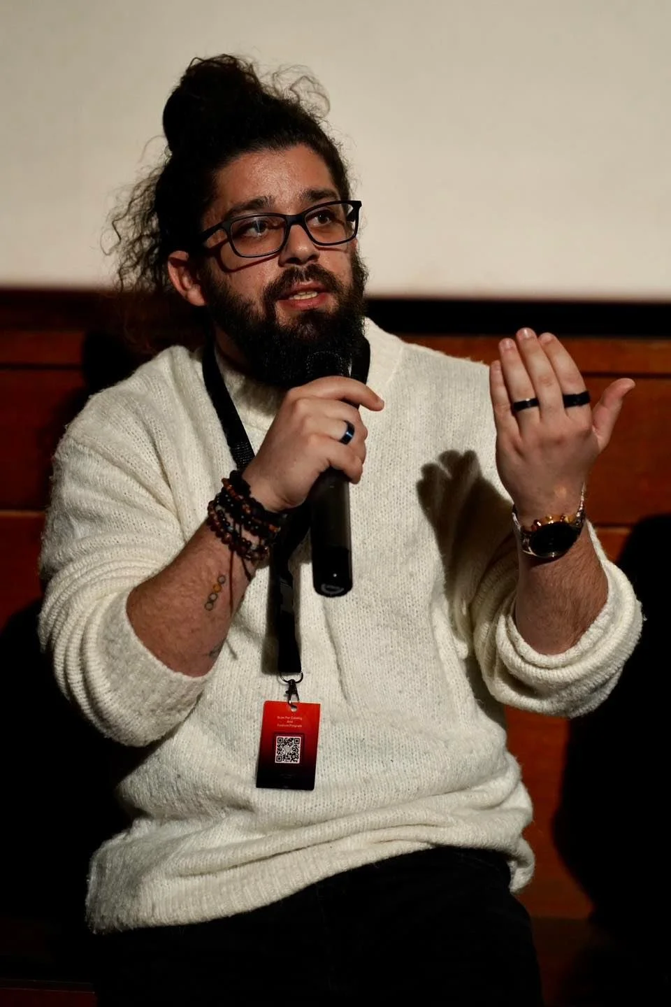 Woman painting on a large beige canvas at night, with art supplies on a small table nearby.