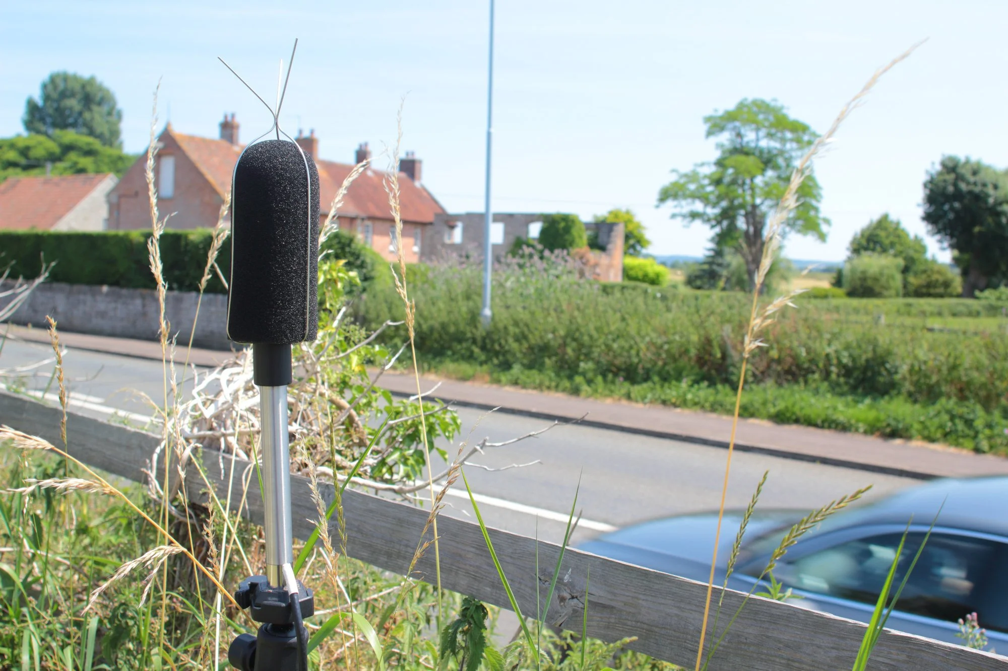 Scenic landscape with a lake, green hills, and mountain range under cloudy sky.