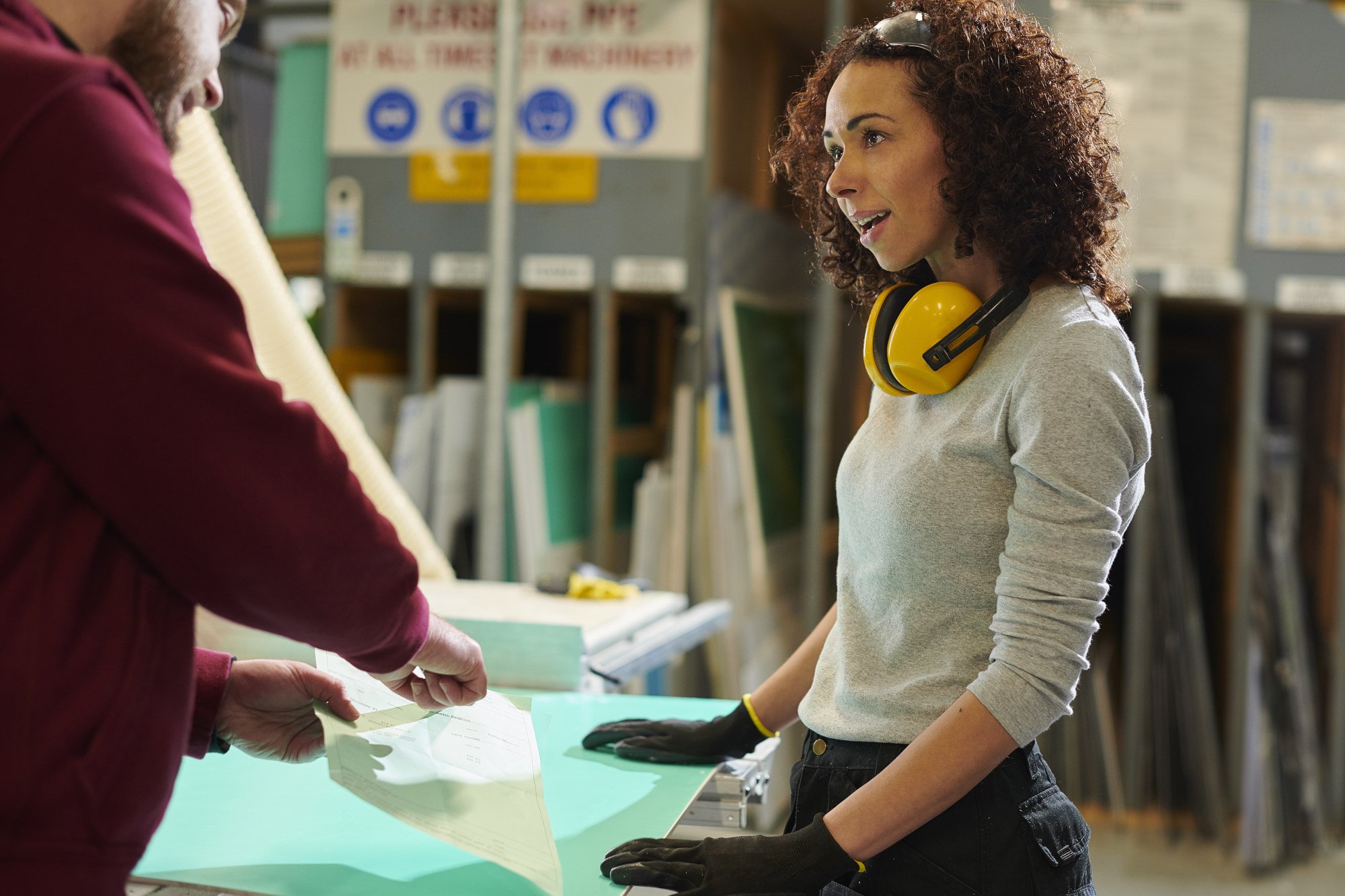 A volcanic landscape with colorful rocks, steam vents, and patches of snow on distant mountains under a cloudy sky.