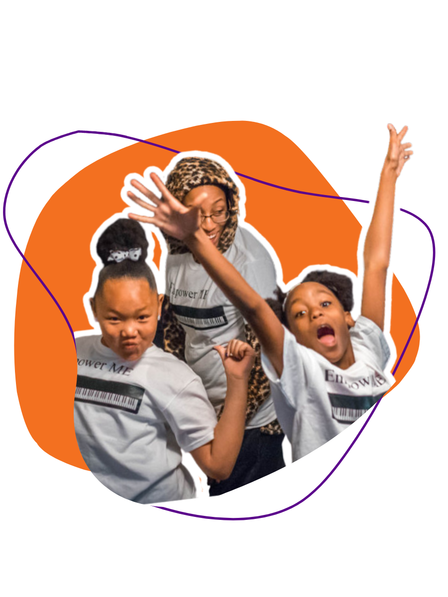 An adult woman and two young girls posing happily, wearing matching white T-shirts with a barcode design that says 'Empower Me.' The woman is wearing glasses and a leopard print hood, while the girls are making energetic gestures and expressions against an orange background.