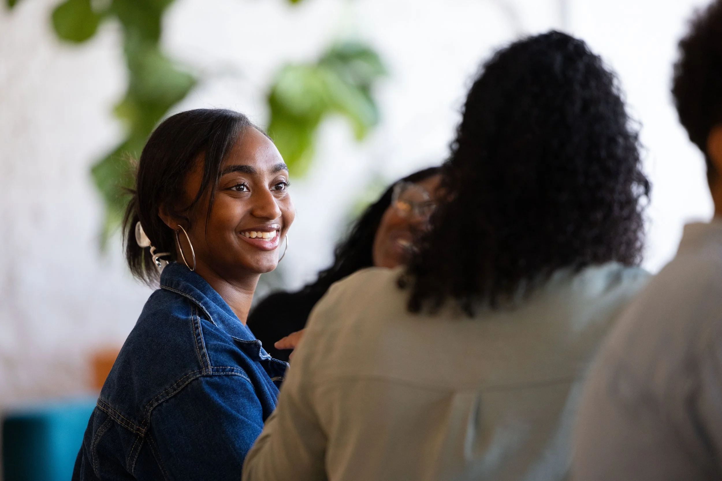 A group of diverse women sitting together and smiling during a discussion or gathering.