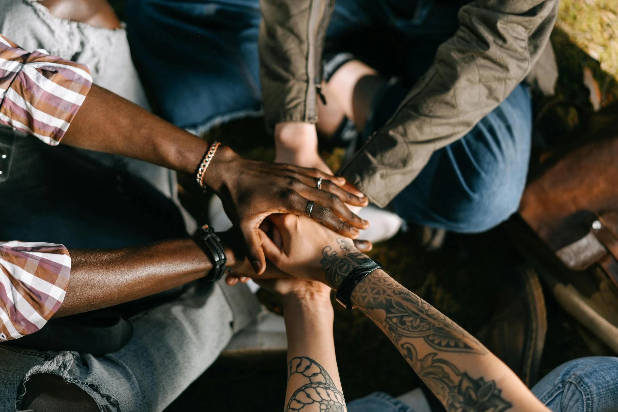 Multiple hands of diverse individuals stacked together in a gesture of unity and support.