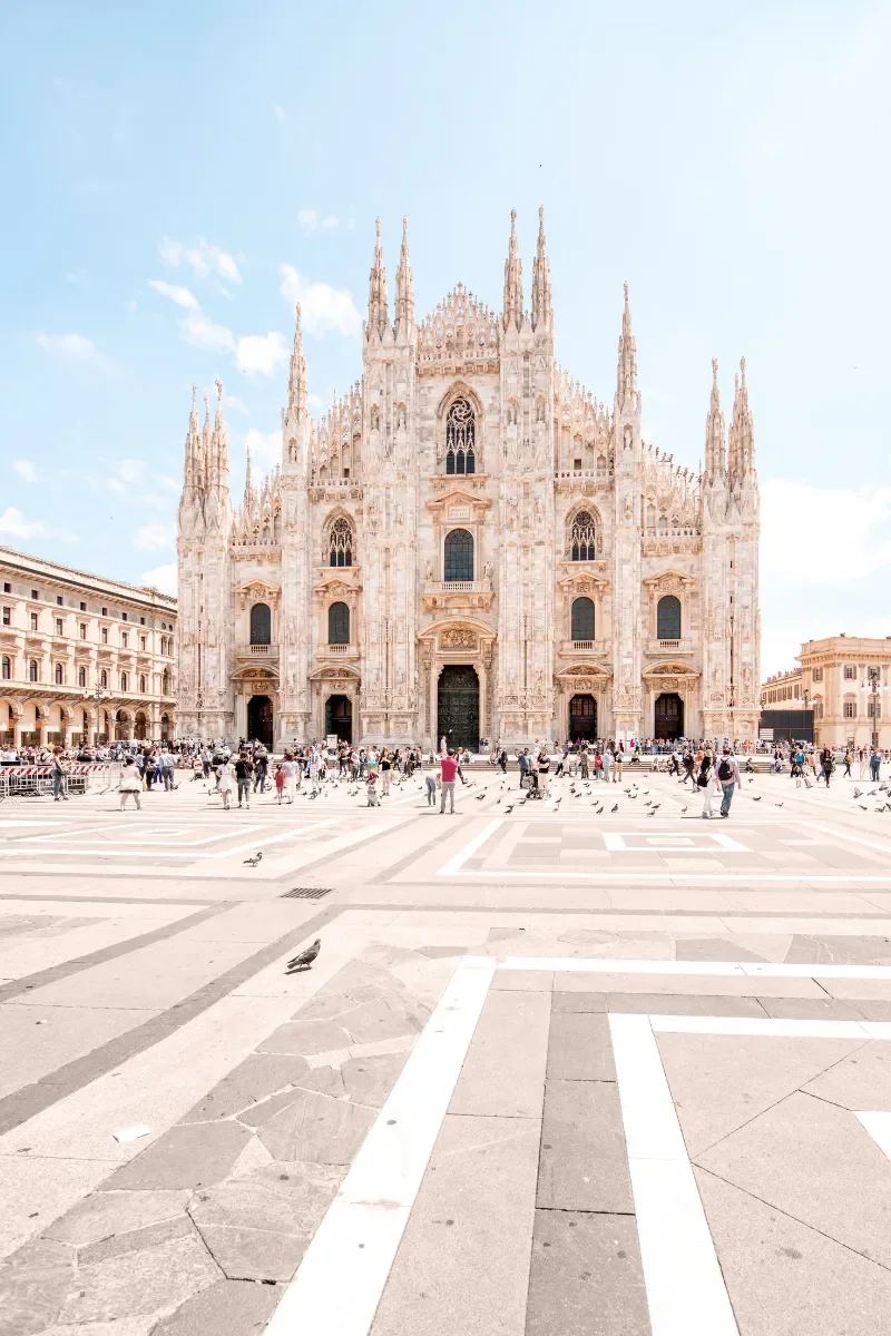 The Florence Cathedral, also known as the Cathedral of Santa Maria del Fiore, in Florence, Italy, with people and pigeons in the square in front.