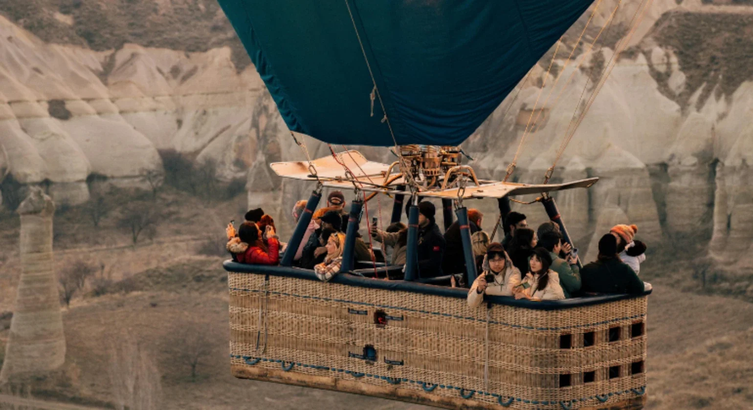 People riding in a hot air balloon over a canyon.