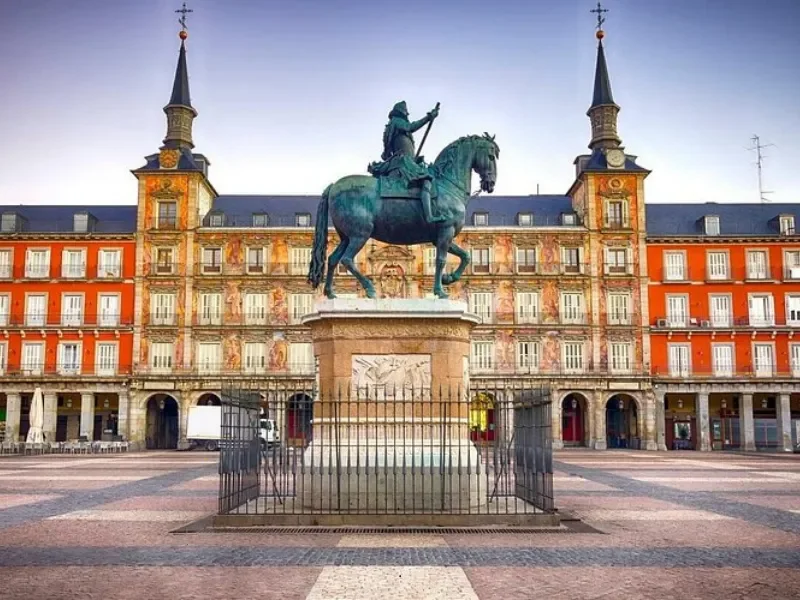 Equestrian statue of a man on horseback in a square with historic buildings in the background.